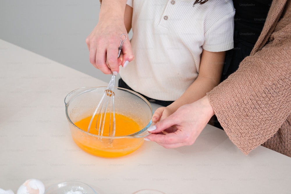 a couple of people that are mixing something in a bowl