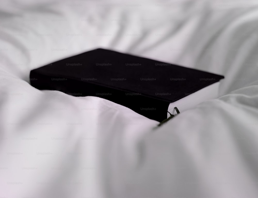 a black book sitting on top of a white bed