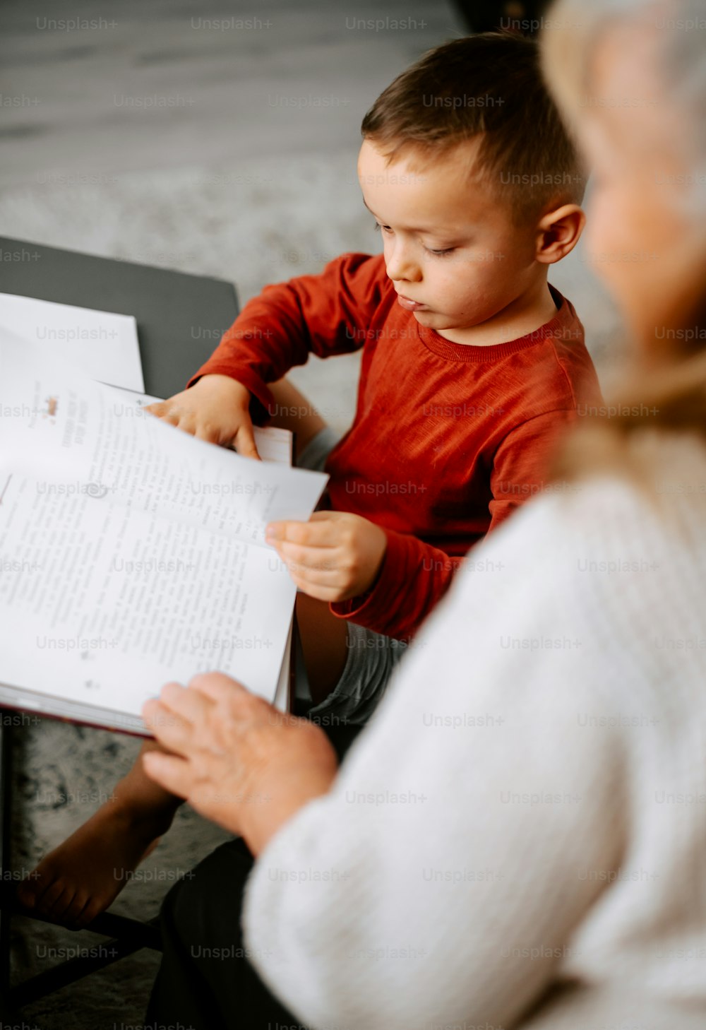 a woman sitting next to a little boy holding a piece of paper