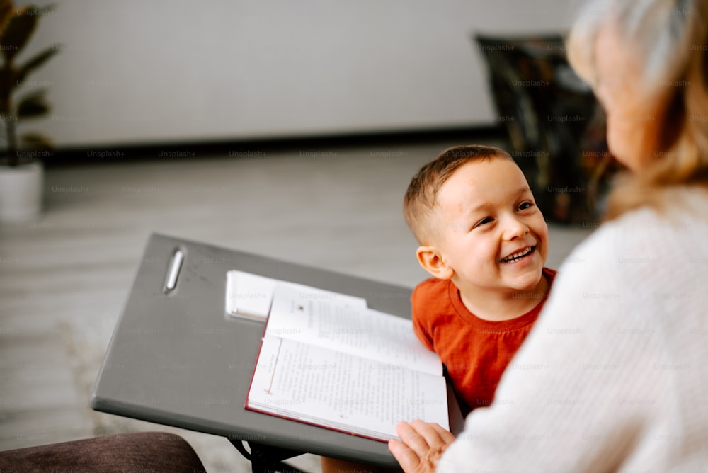 a woman sitting next to a little boy holding a book