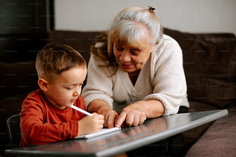 Eine ältere Frau und ein kleiner Junge sitzen an einem Tisch