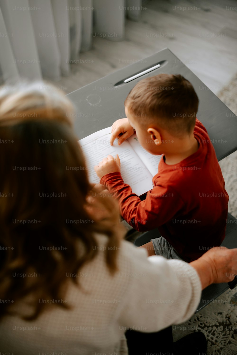 a young boy sitting at a table writing on a piece of paper