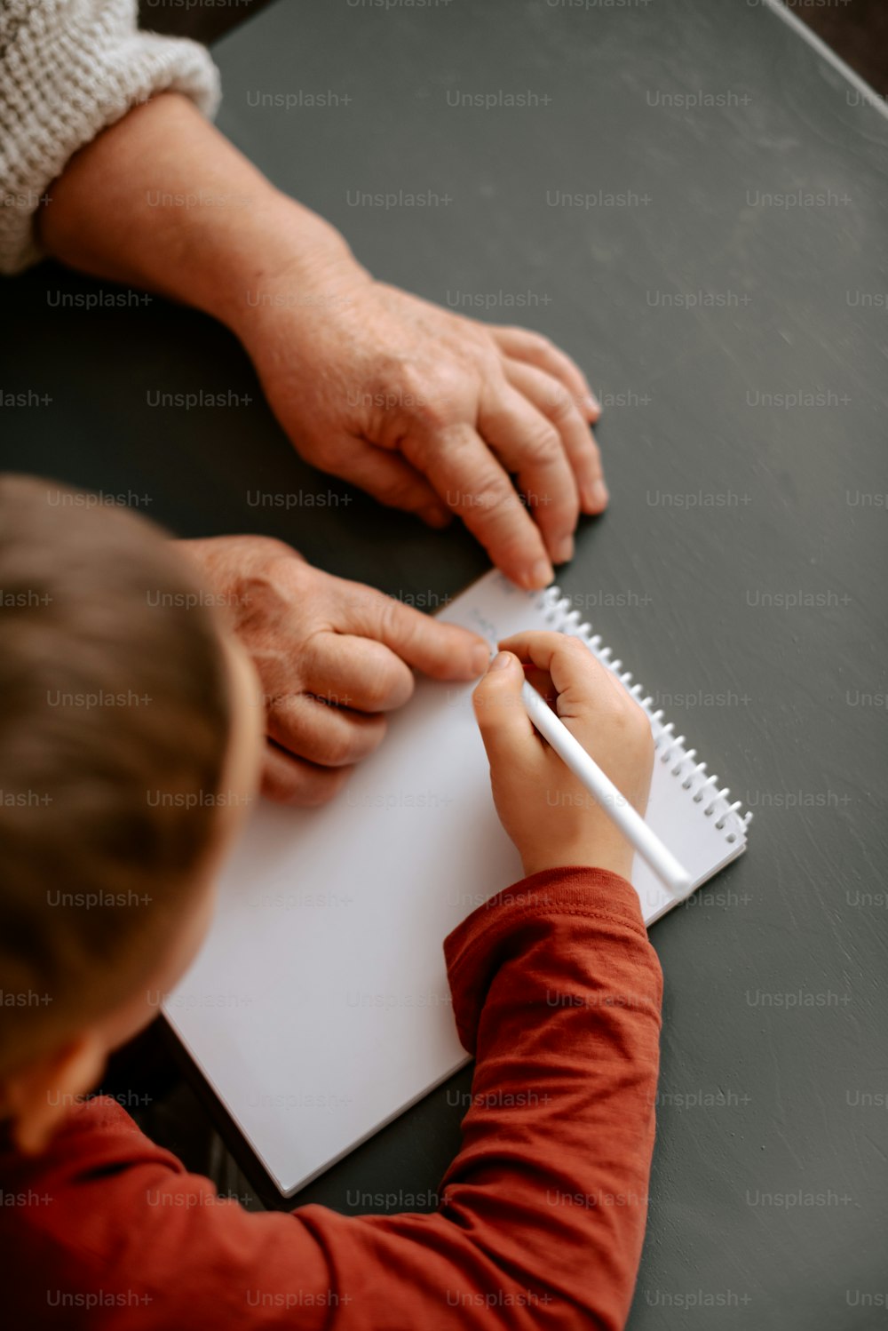 Un bambino sta scrivendo su un blocco note con una matita