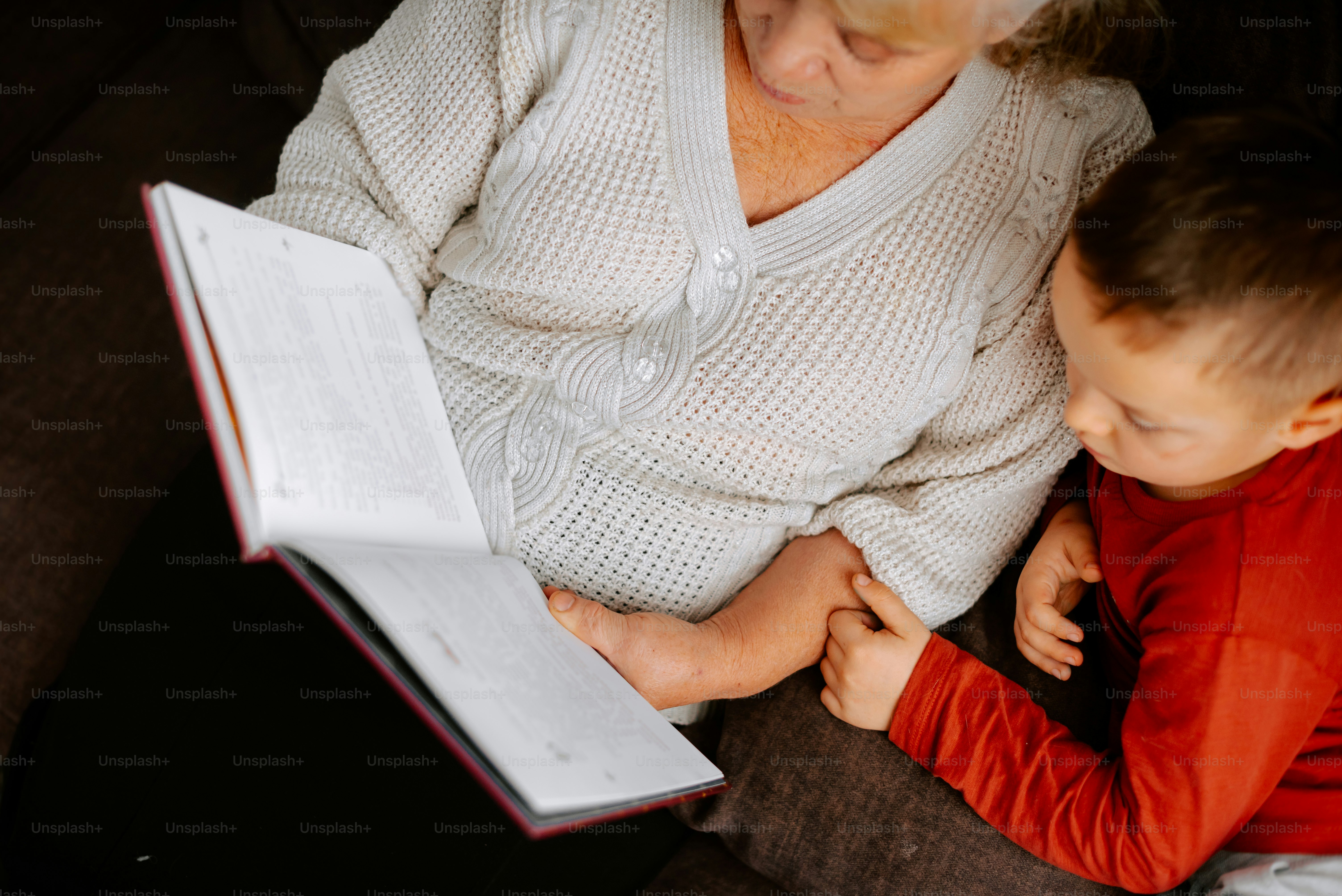 a woman and a child are looking at a book