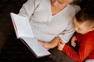 a woman and a child are looking at a book