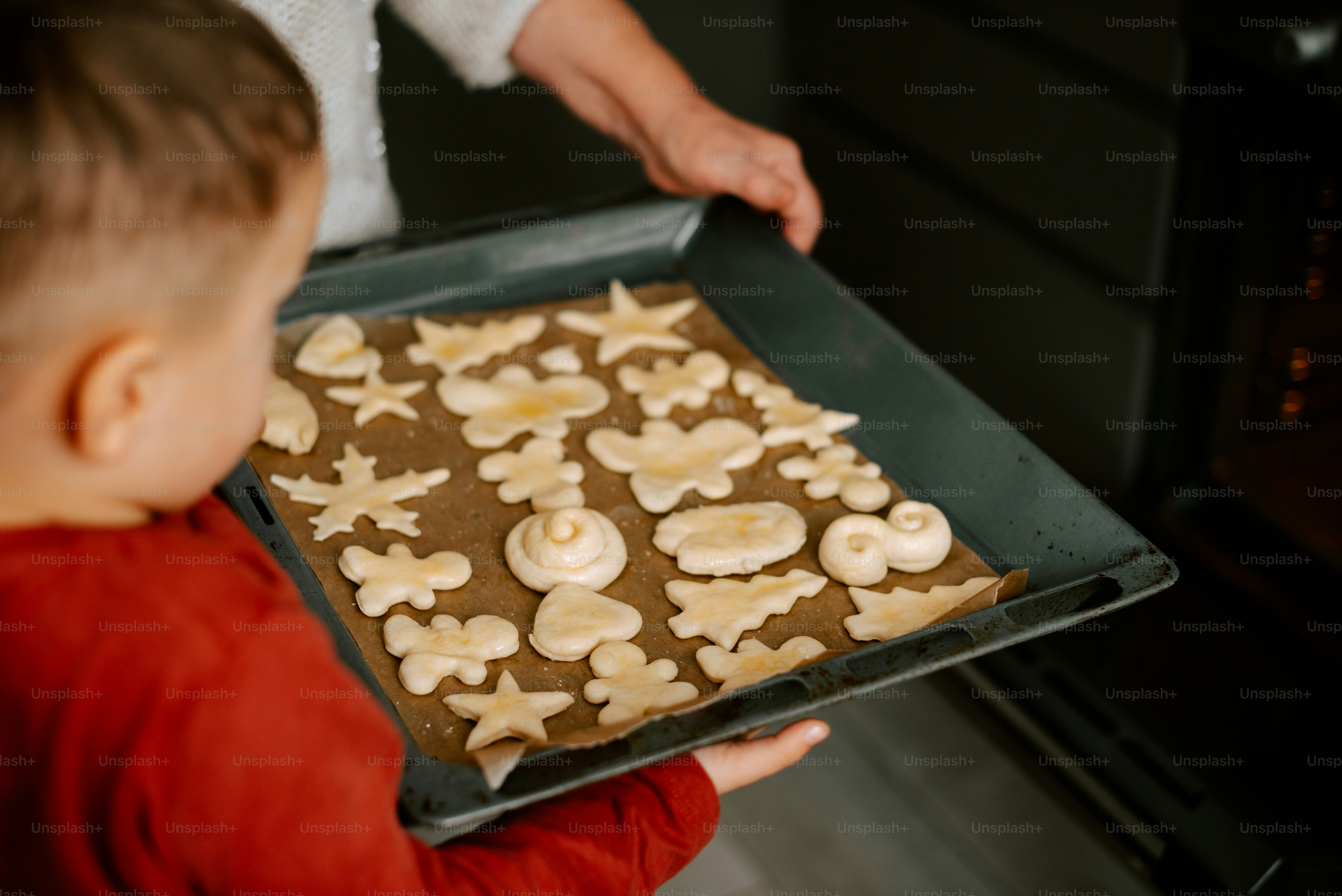 a young boy holding a tray of cookies