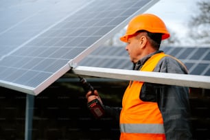 a man in an orange safety vest and hard hat working on a solar panel