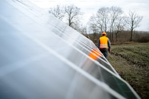 Un hombre parado junto a una hilera de paneles solares