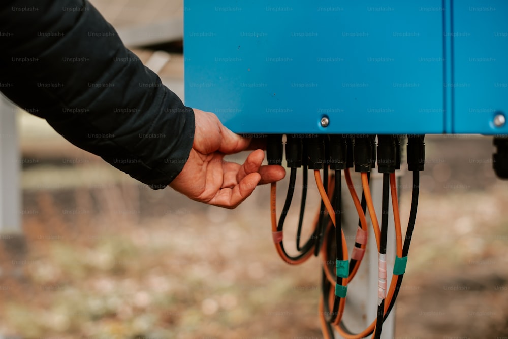a person holding a blue box with wires attached to it