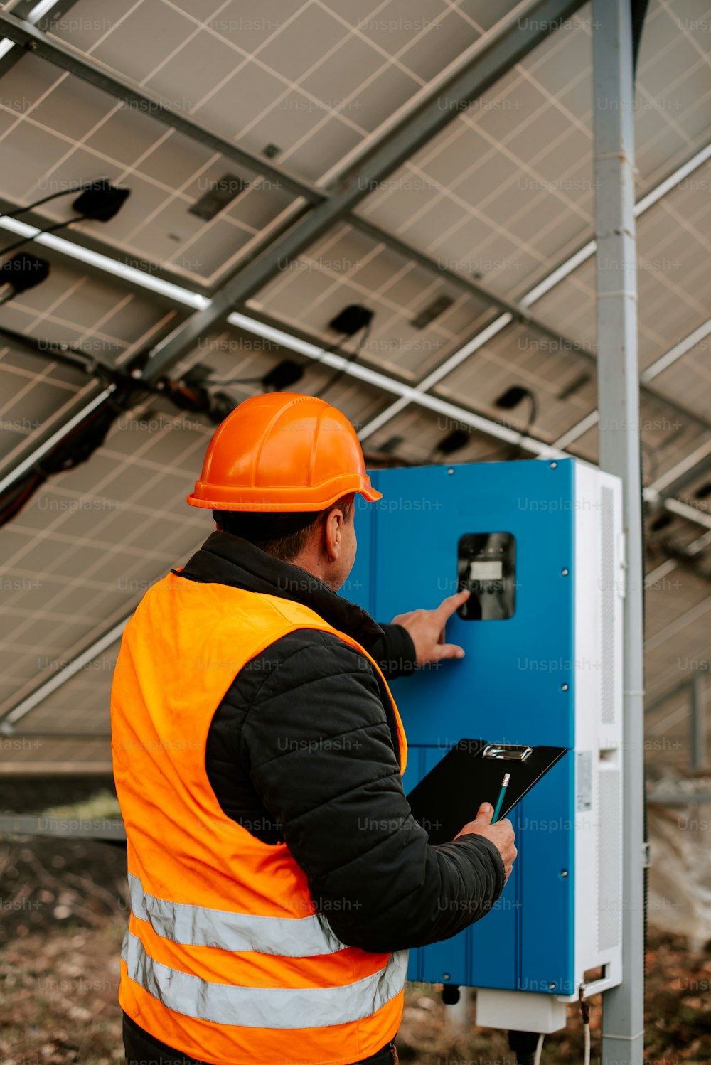 a man in an orange safety vest is looking at a blue box