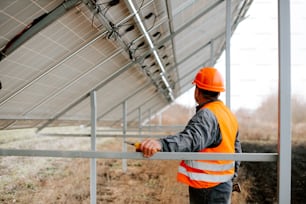 a man in an orange safety vest and hard hat standing in front of a solar