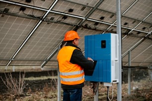 Ein Mann in einer orangefarbenen Warnweste arbeitet an einem Solarpanel