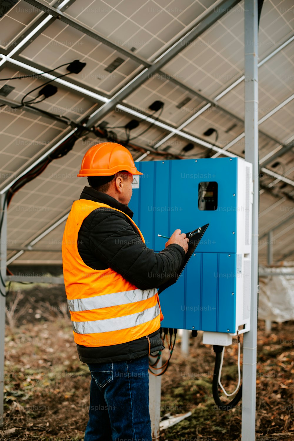 a man in a hard hat and safety vest working on a solar panel