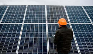 a man wearing a hard hat standing in front of a solar panel