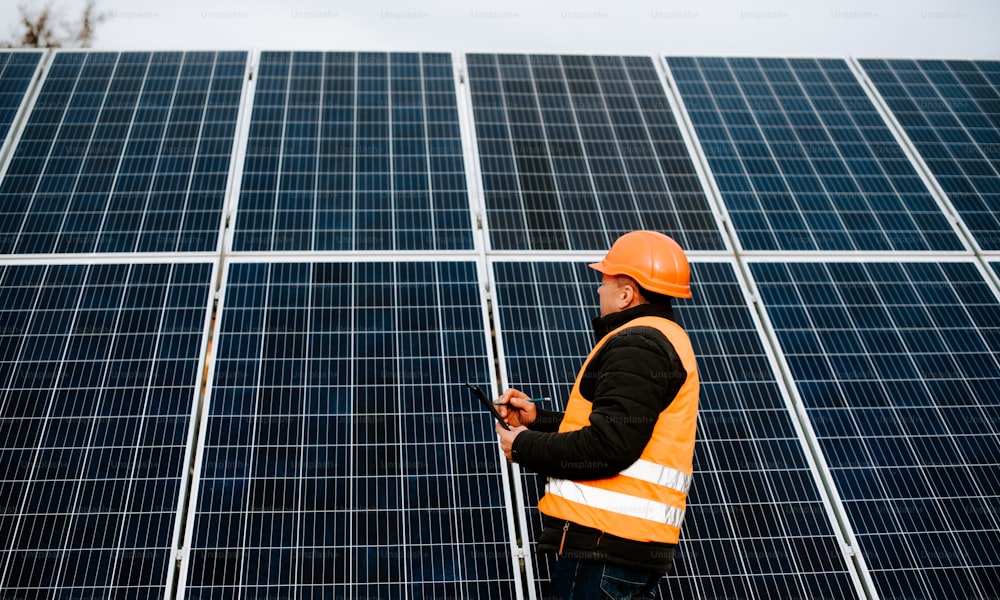 a man in a hard hat standing in front of a solar panel