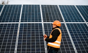 a man in a hard hat standing in front of a solar panel