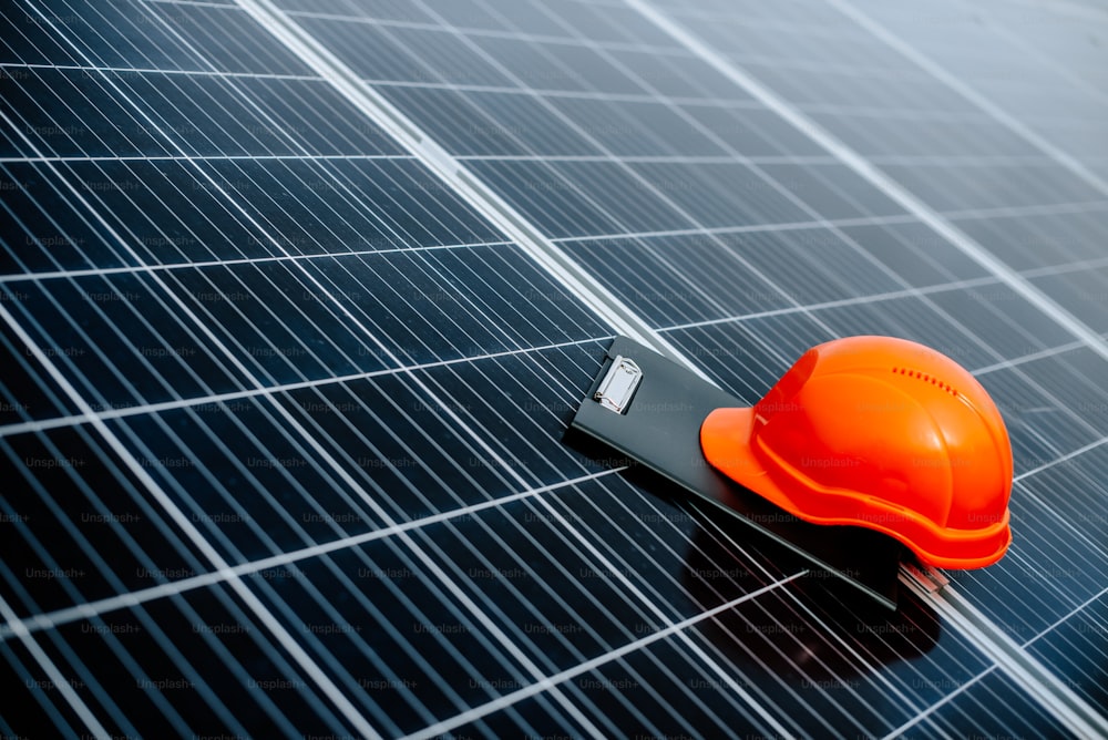 Un casco naranja sentado encima de un panel solar