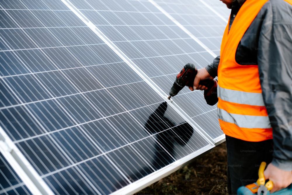 a man in an orange vest is working on a solar panel