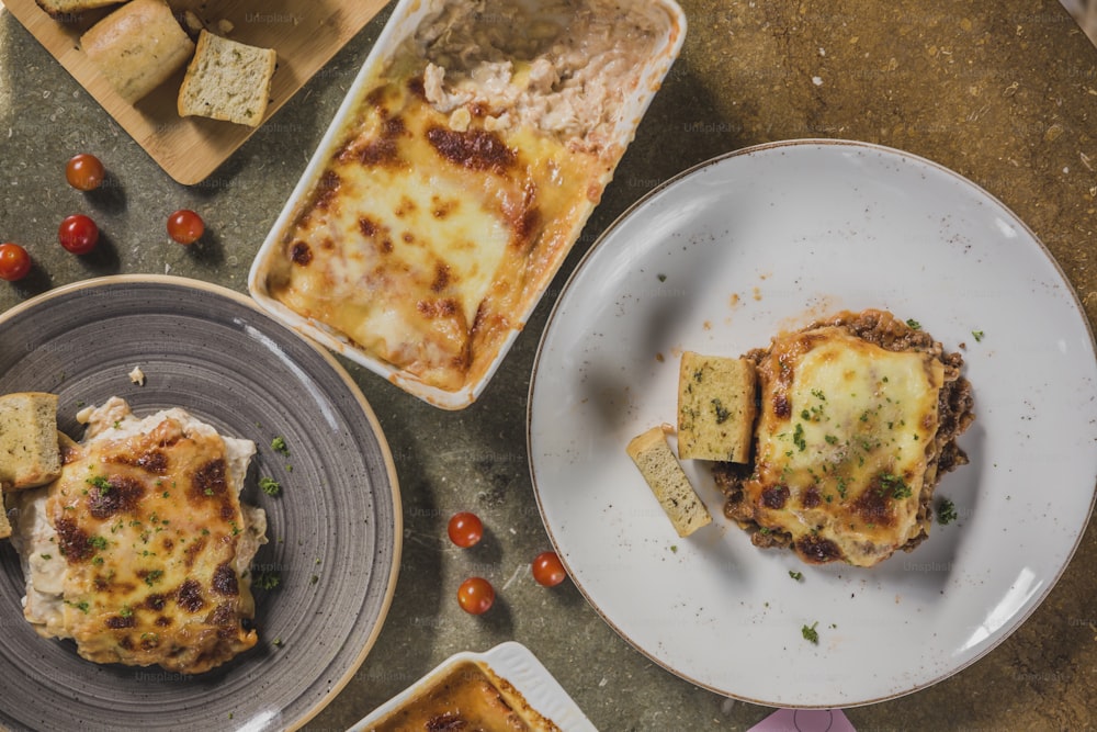 a table topped with plates of food covered in lasagna