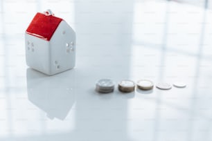 a small house sitting on top of a table next to some coins