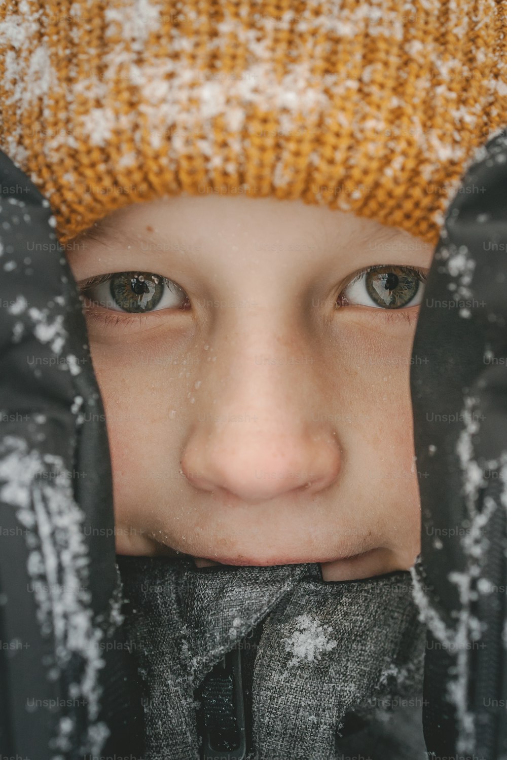 a young boy wearing a hat and gloves covered in snow