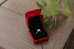 une boîte à bague en velours rouge avec un diamant blanc dedans