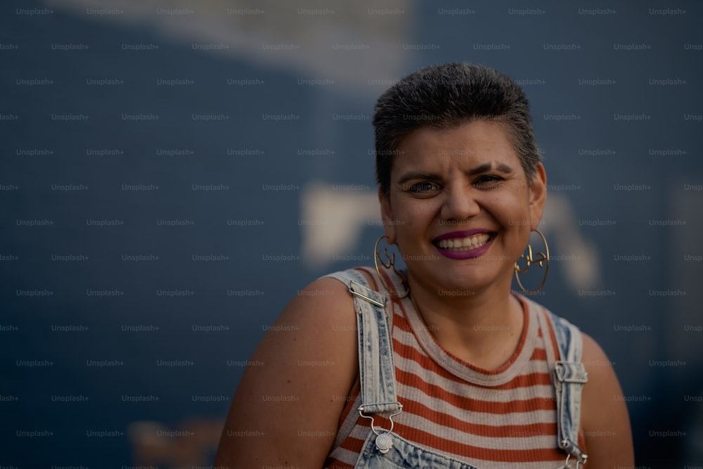 a woman wearing overalls and smiling at the camera