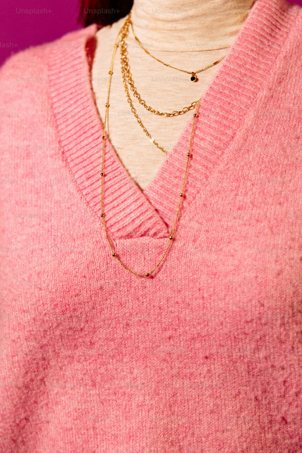 a close up of a person wearing a pink sweater