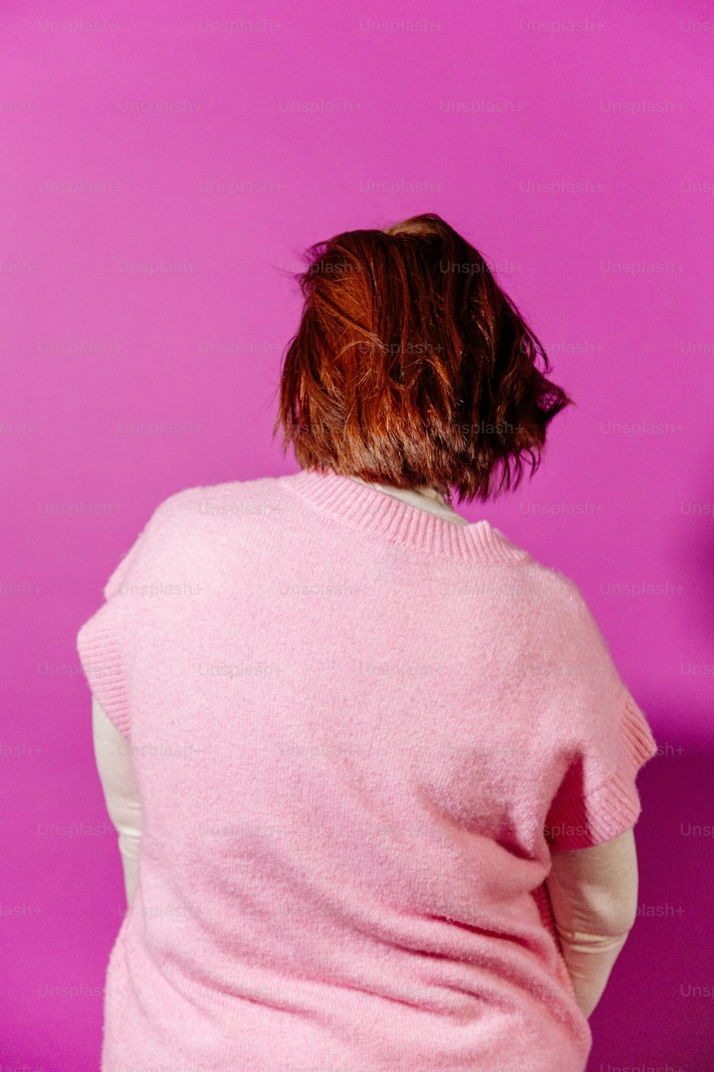 uma mulher em um suéter rosa está sentada