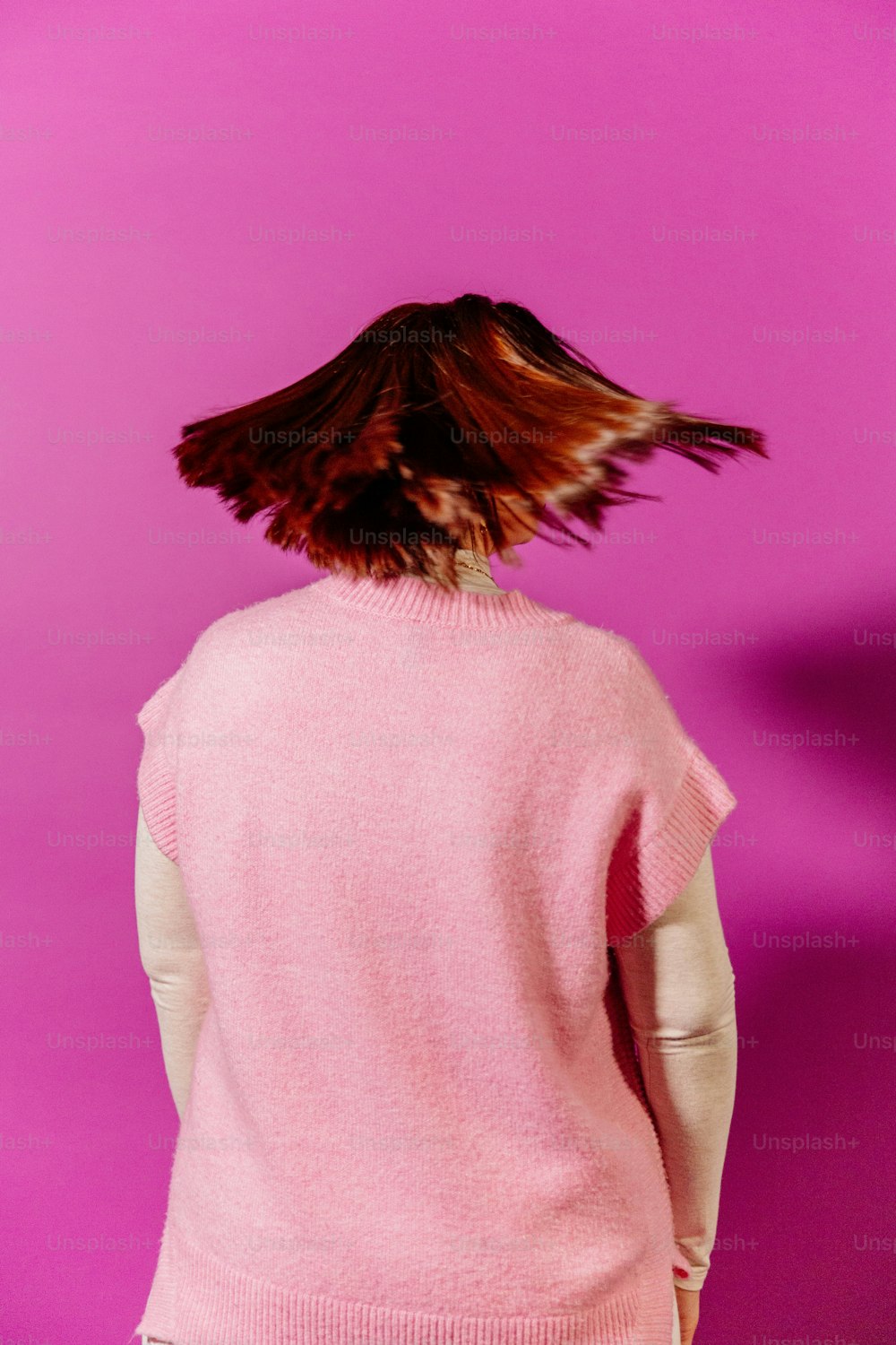 a woman in a pink sweater with a bird on her head