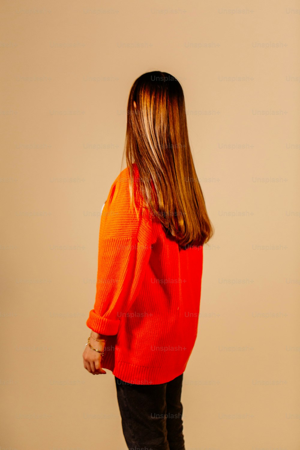 Una donna in un maglione arancione è in piedi
