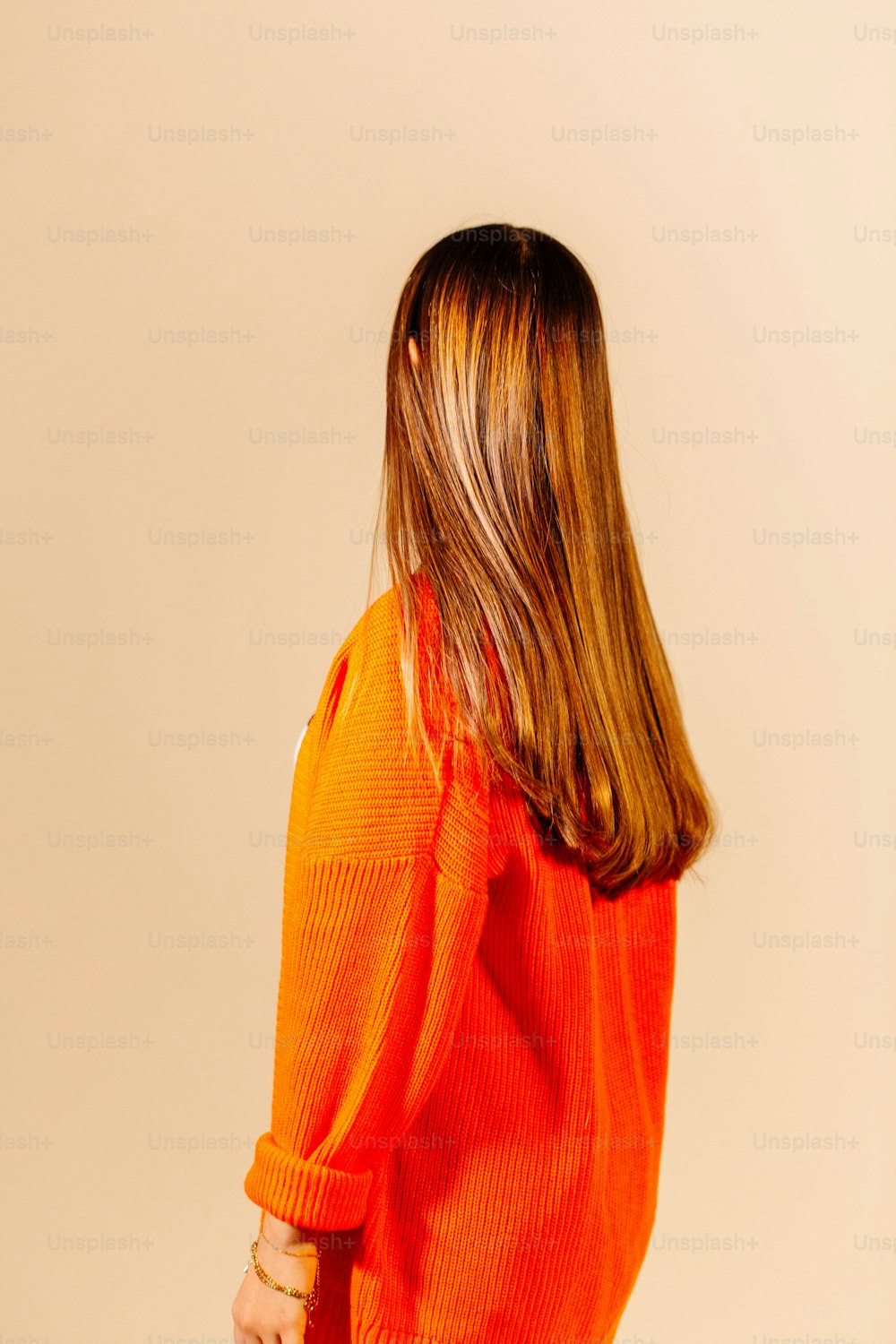a parte de trás da cabeça de uma mulher vestindo um suéter laranja
