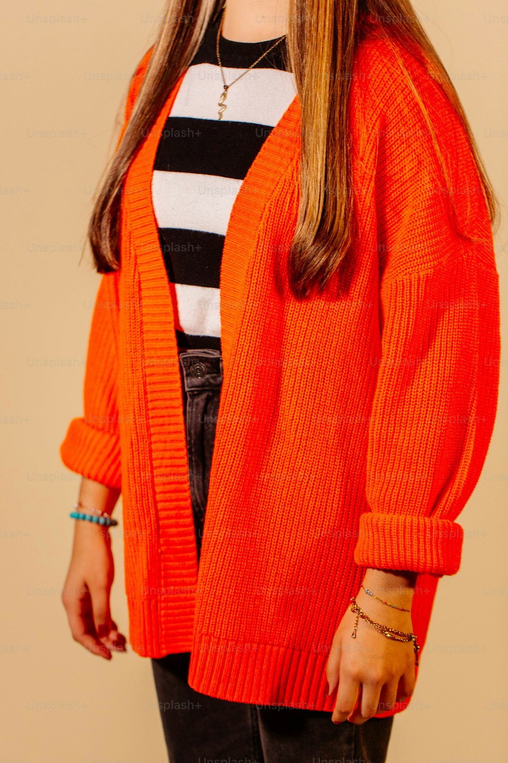 a woman wearing an orange sweater and black pants