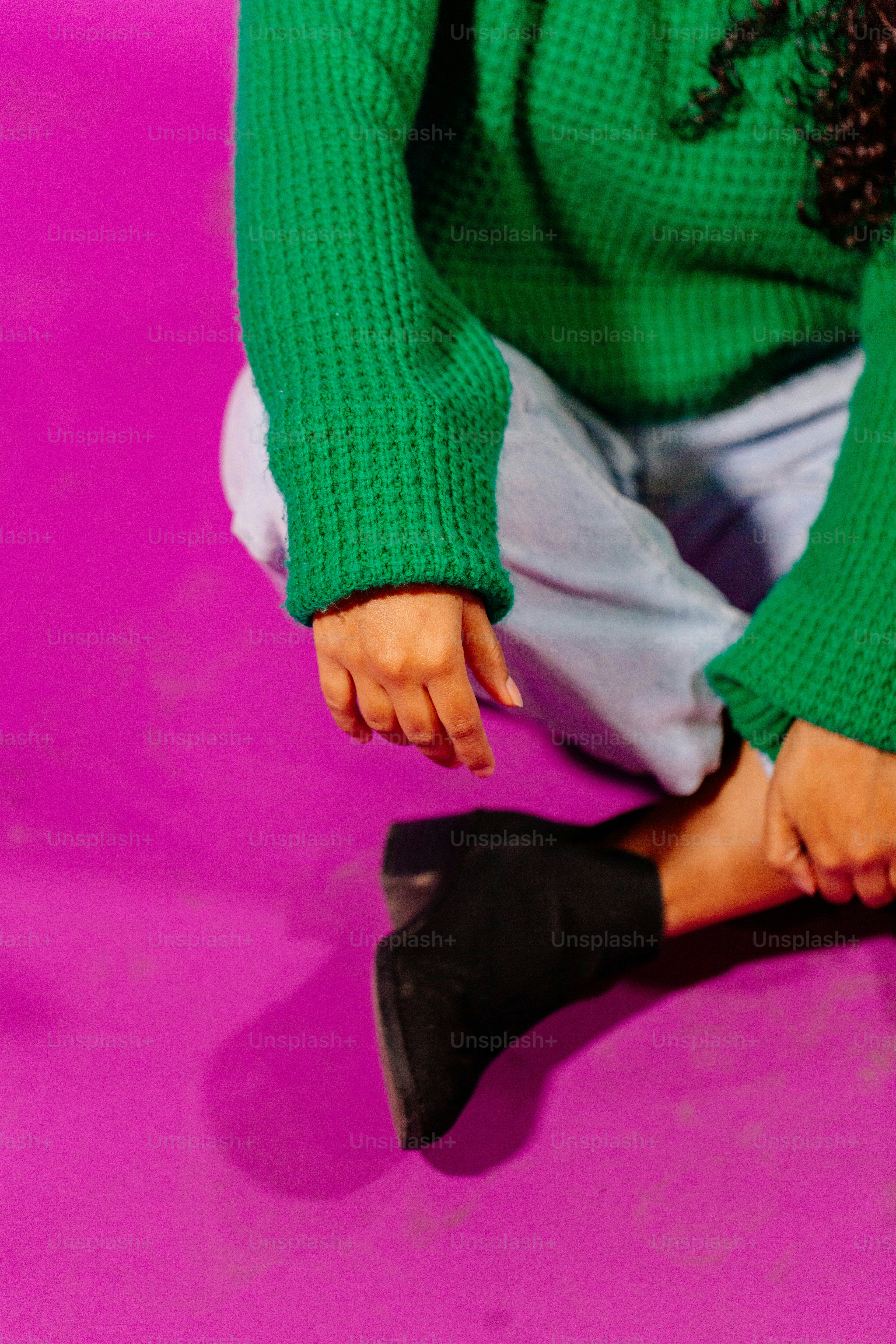 una donna in un maglione verde seduta sul pavimento