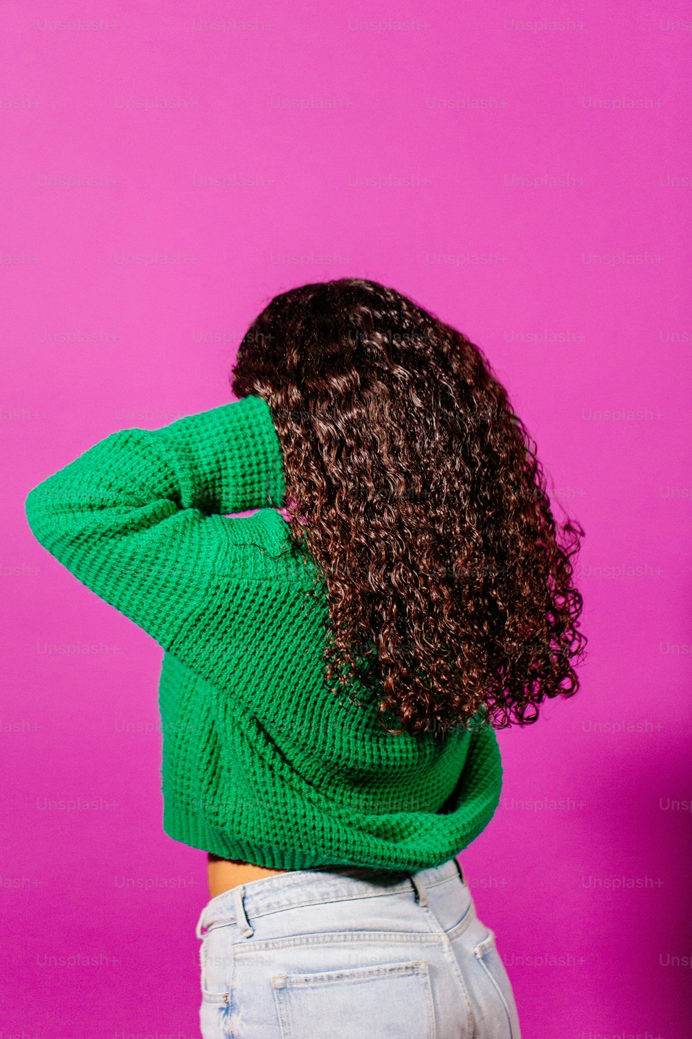 a woman with curly hair wearing a green sweater