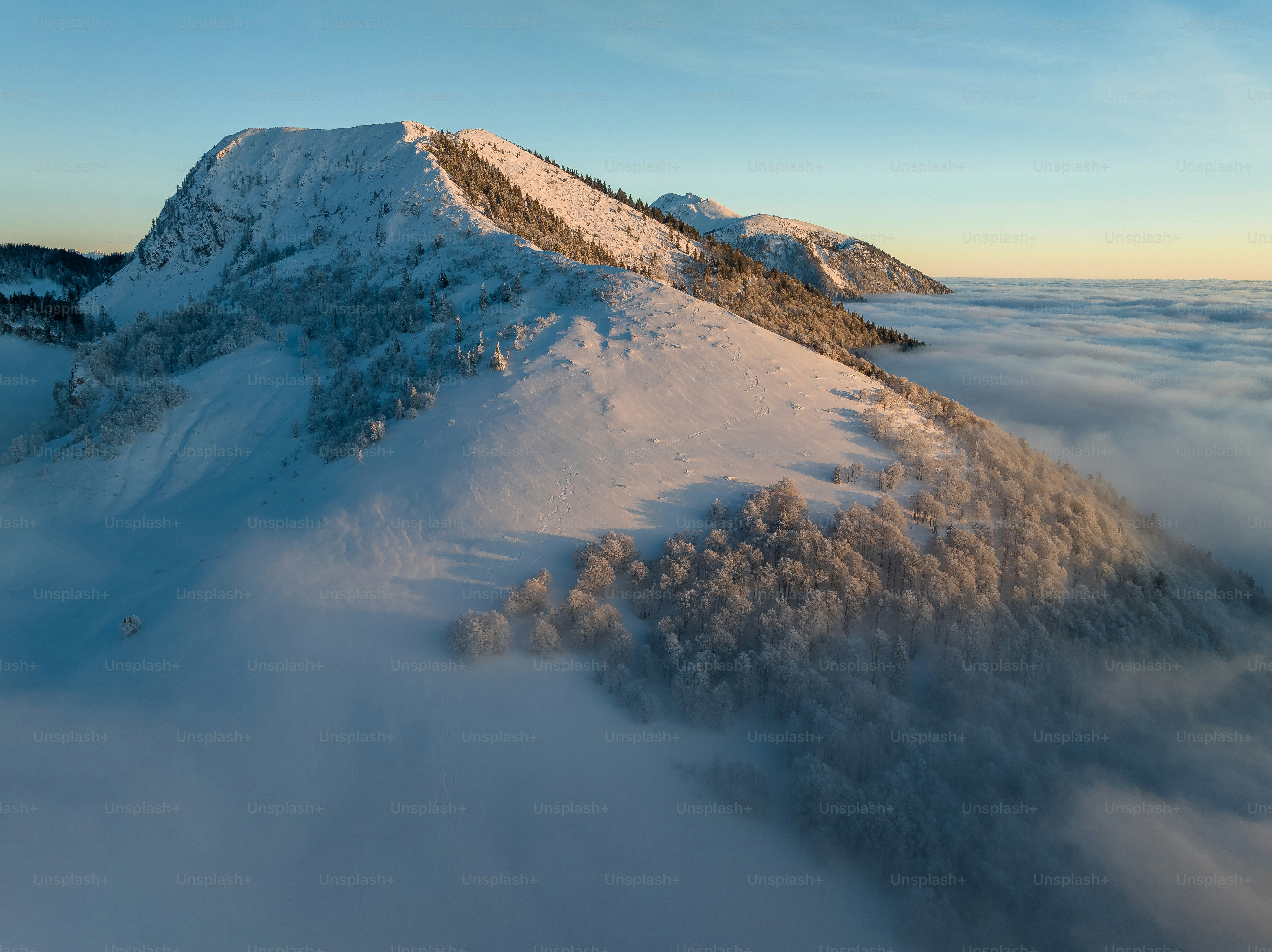 a mountain covered in snow and surrounded by clouds