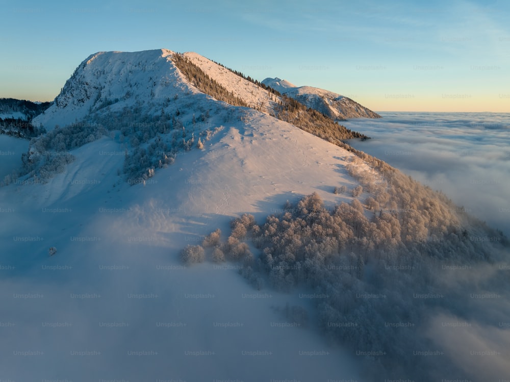 uma montanha coberta de neve e cercada por nuvens