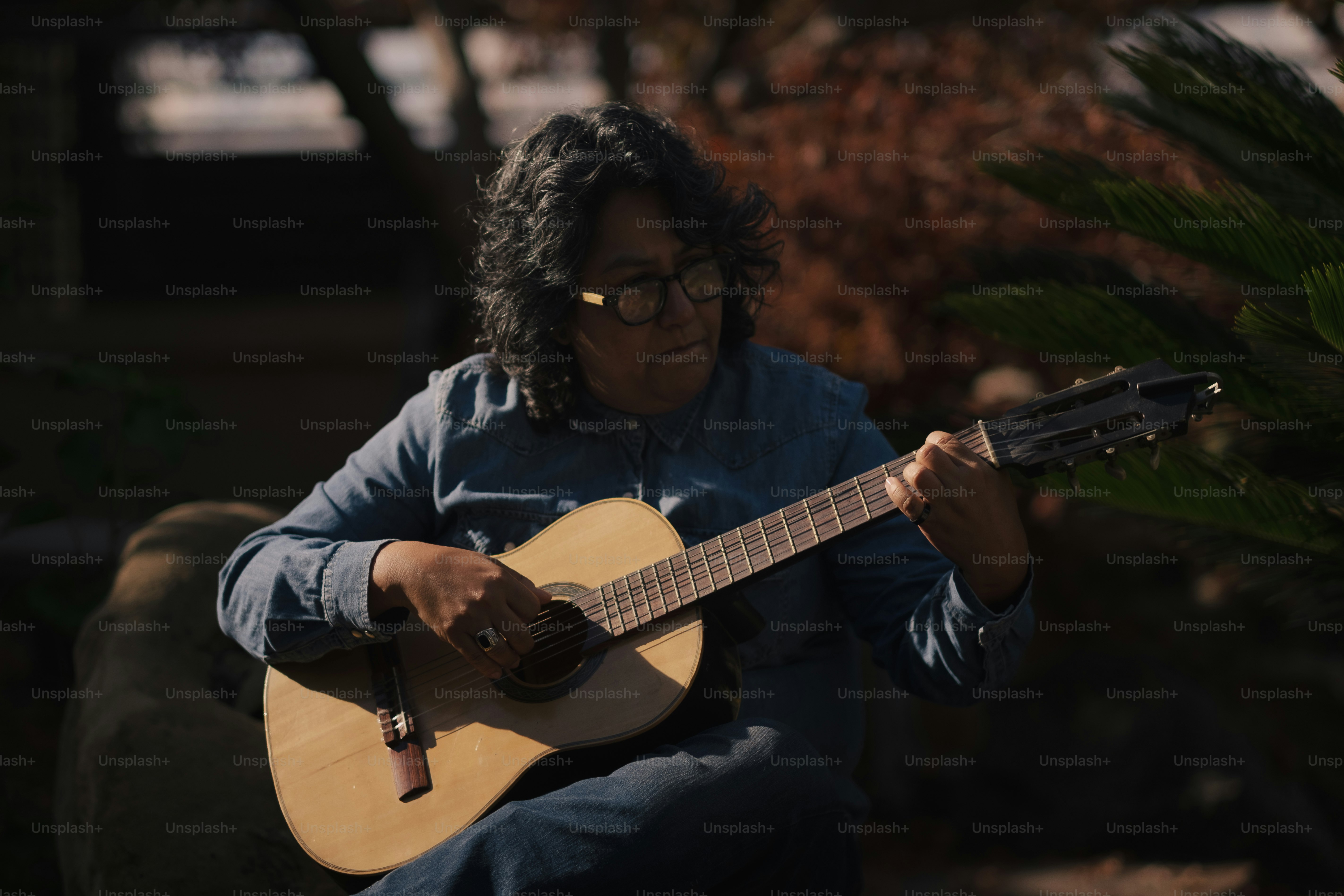 a woman with glasses playing a guitar outside