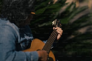a person playing a guitar in front of a tree