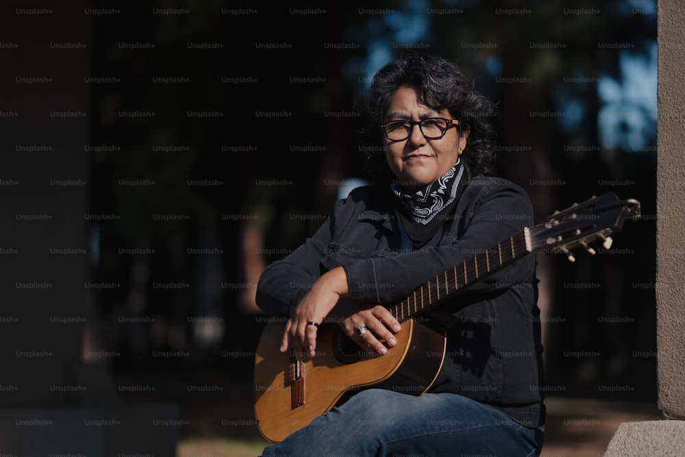 una donna seduta a terra che suona una chitarra