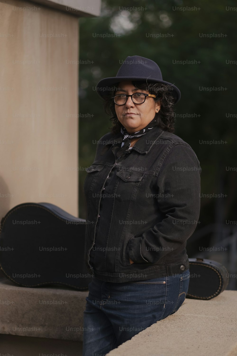a woman with a hat and glasses standing next to a guitar