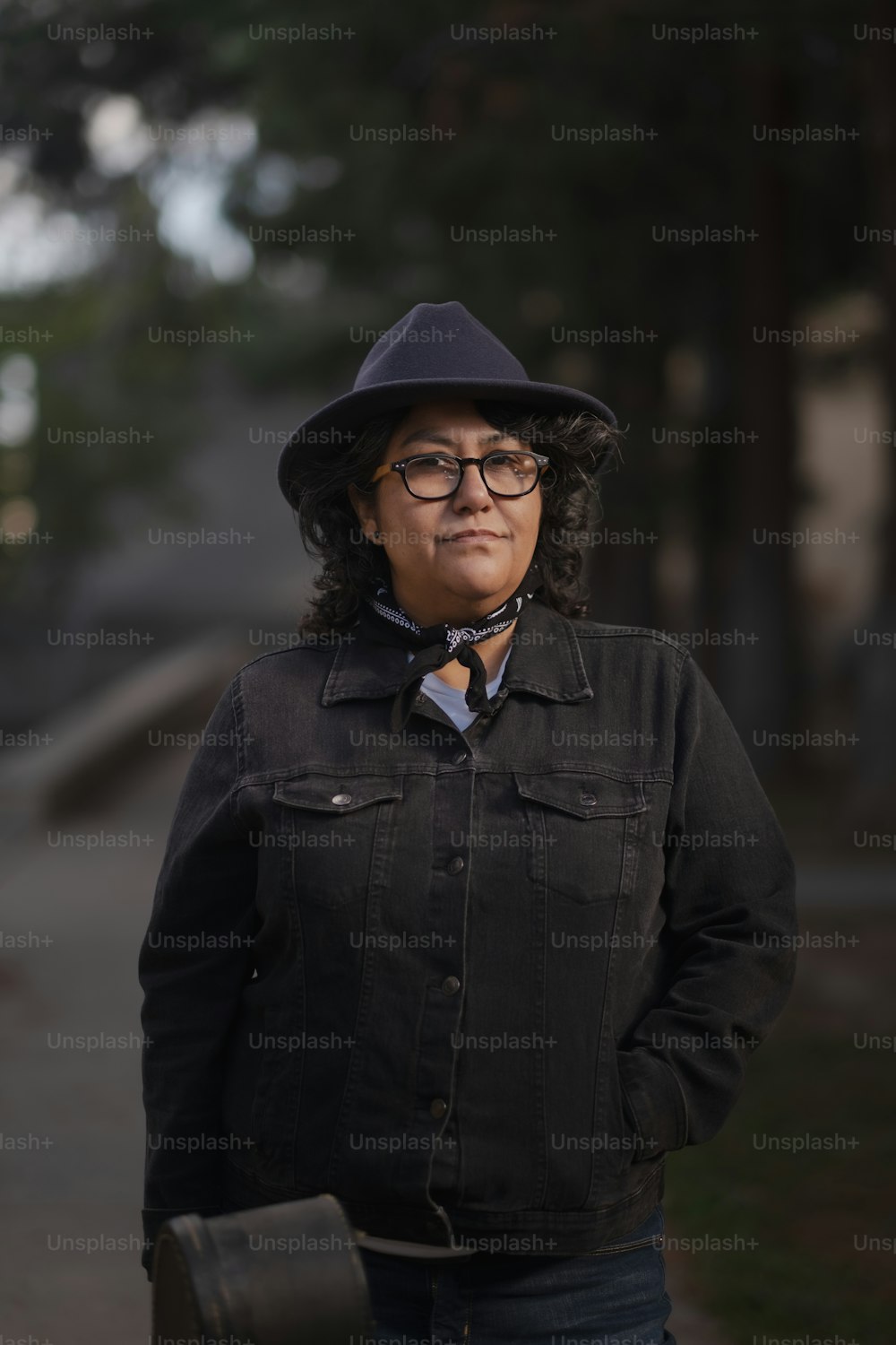 Eine Frau mit Hut und Brille steht auf einem Bürgersteig