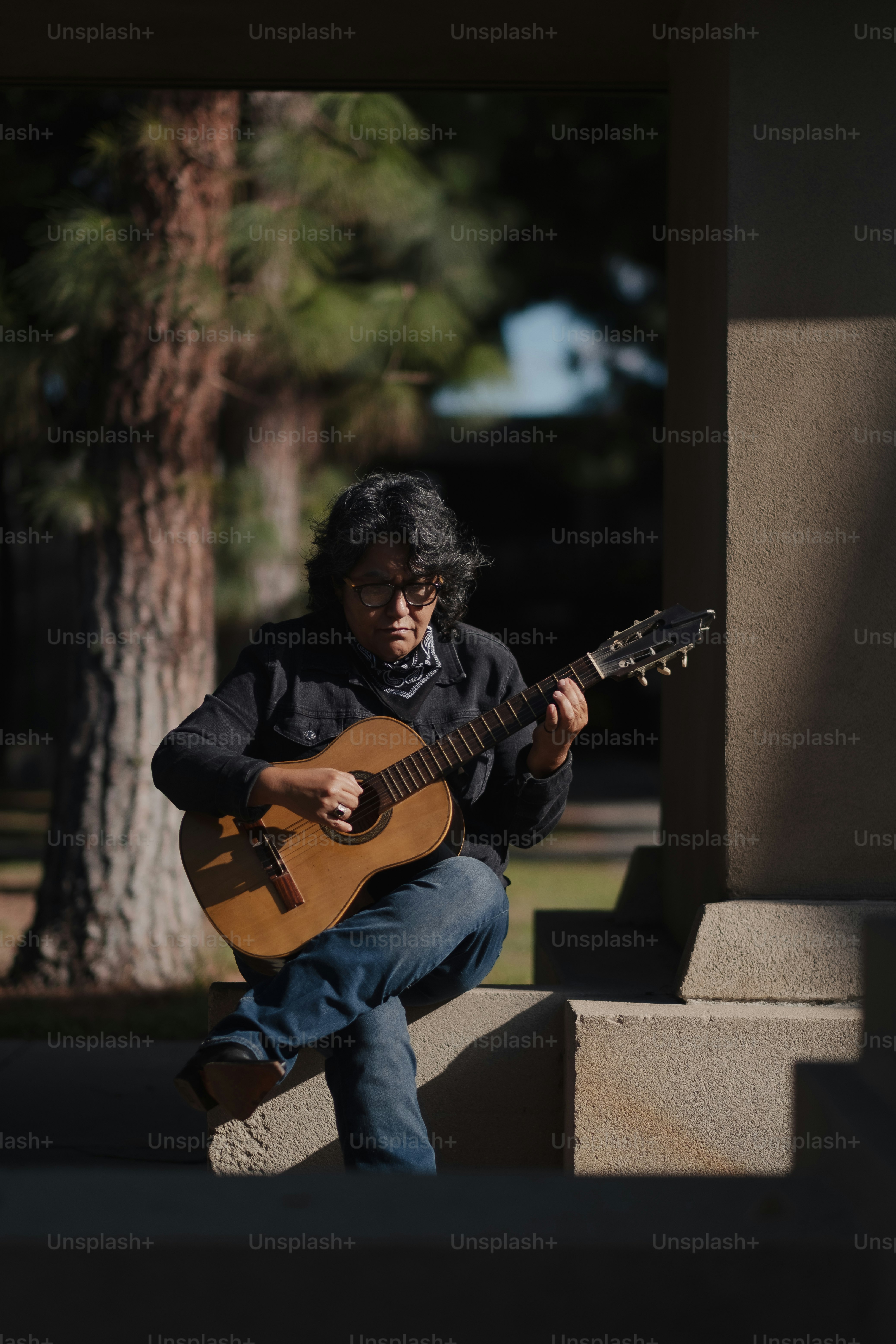 A man sitting on steps playing a guitar photo – Playing guitar Image on ...