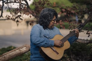 a man playing a guitar under a tree