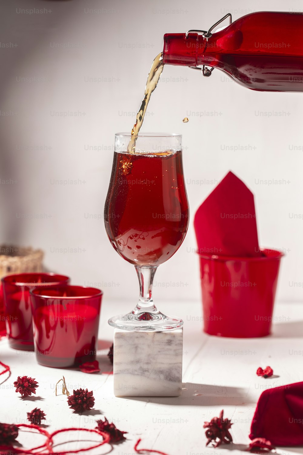 uma bebida vermelha sendo derramada em um copo de vinho