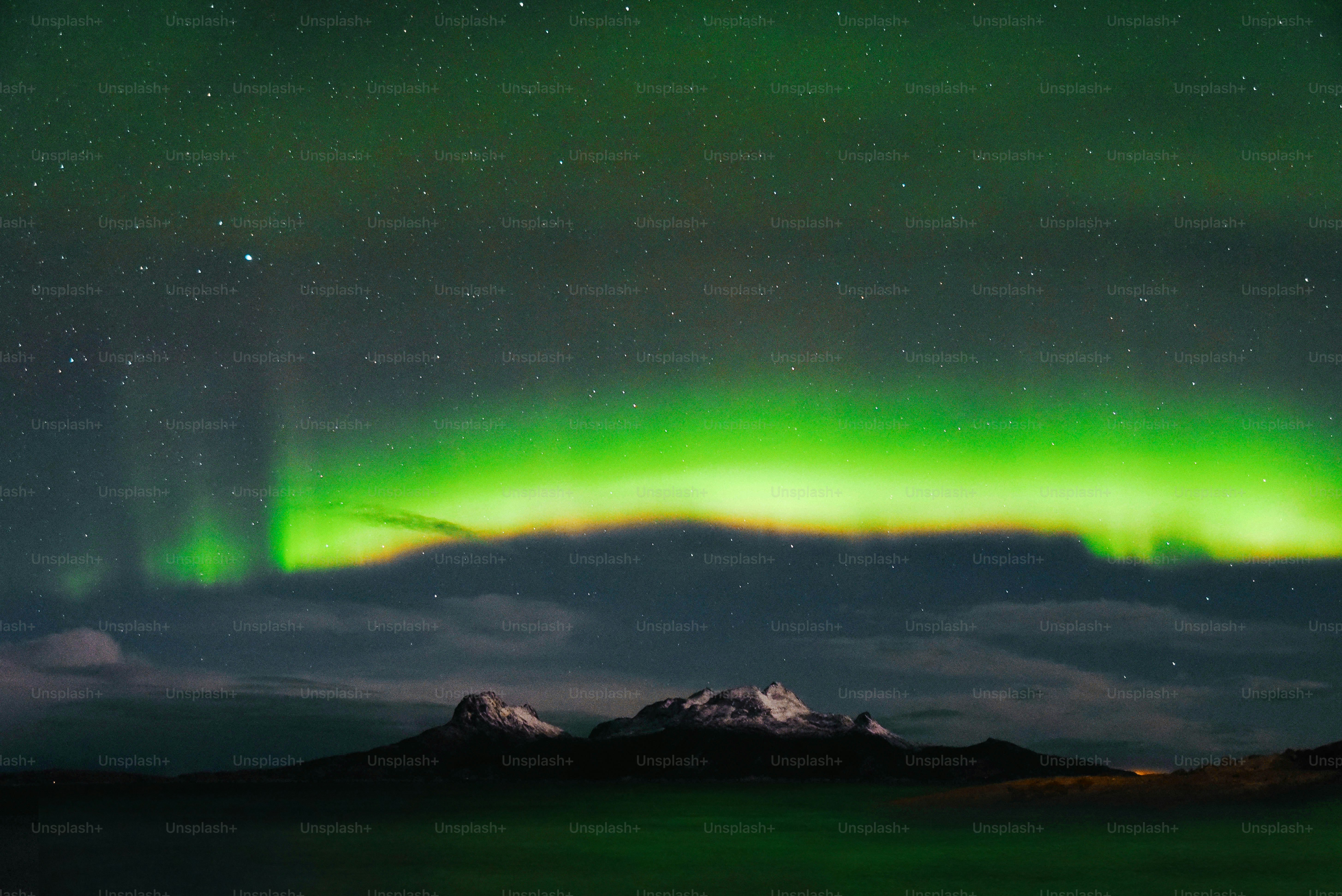 a green and purple aurora over a mountain range