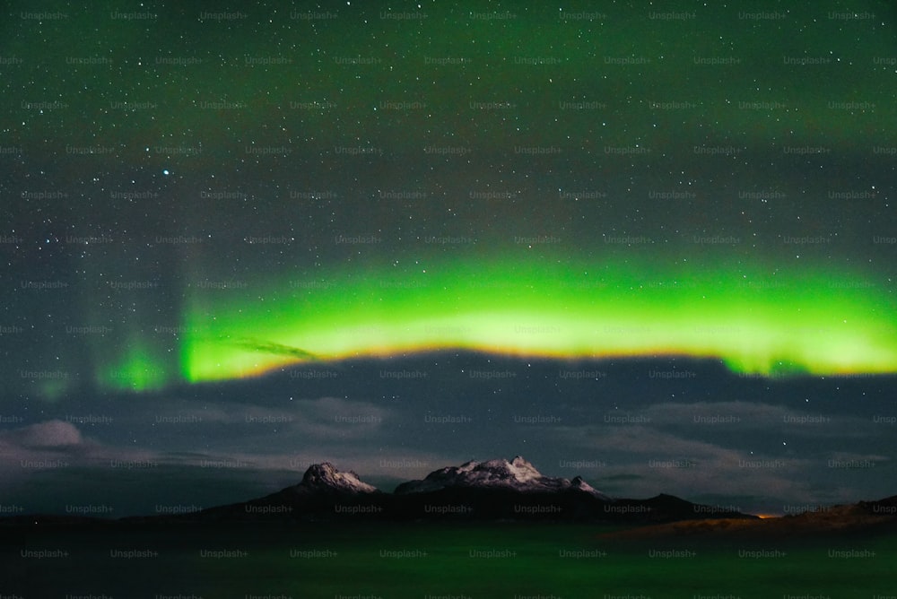 a green and purple aurora over a mountain range