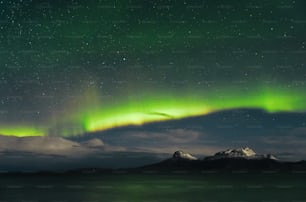 uma aurora verde e roxa pairava sobre uma cordilheira