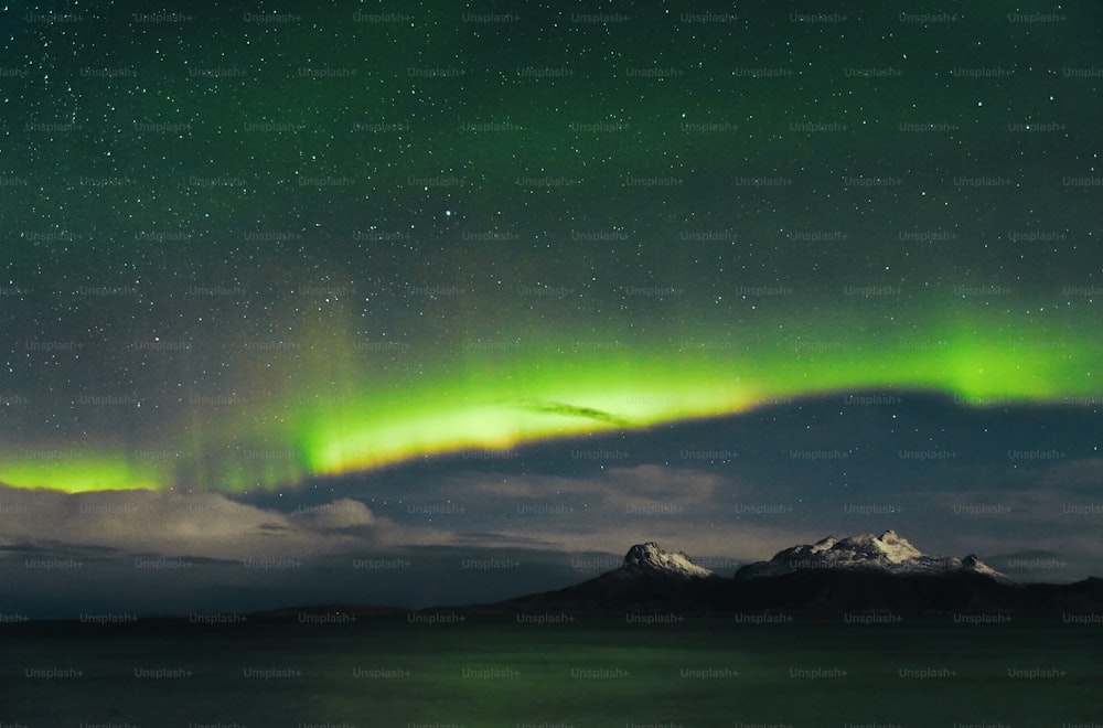 a green and purple aurora bore over a mountain range