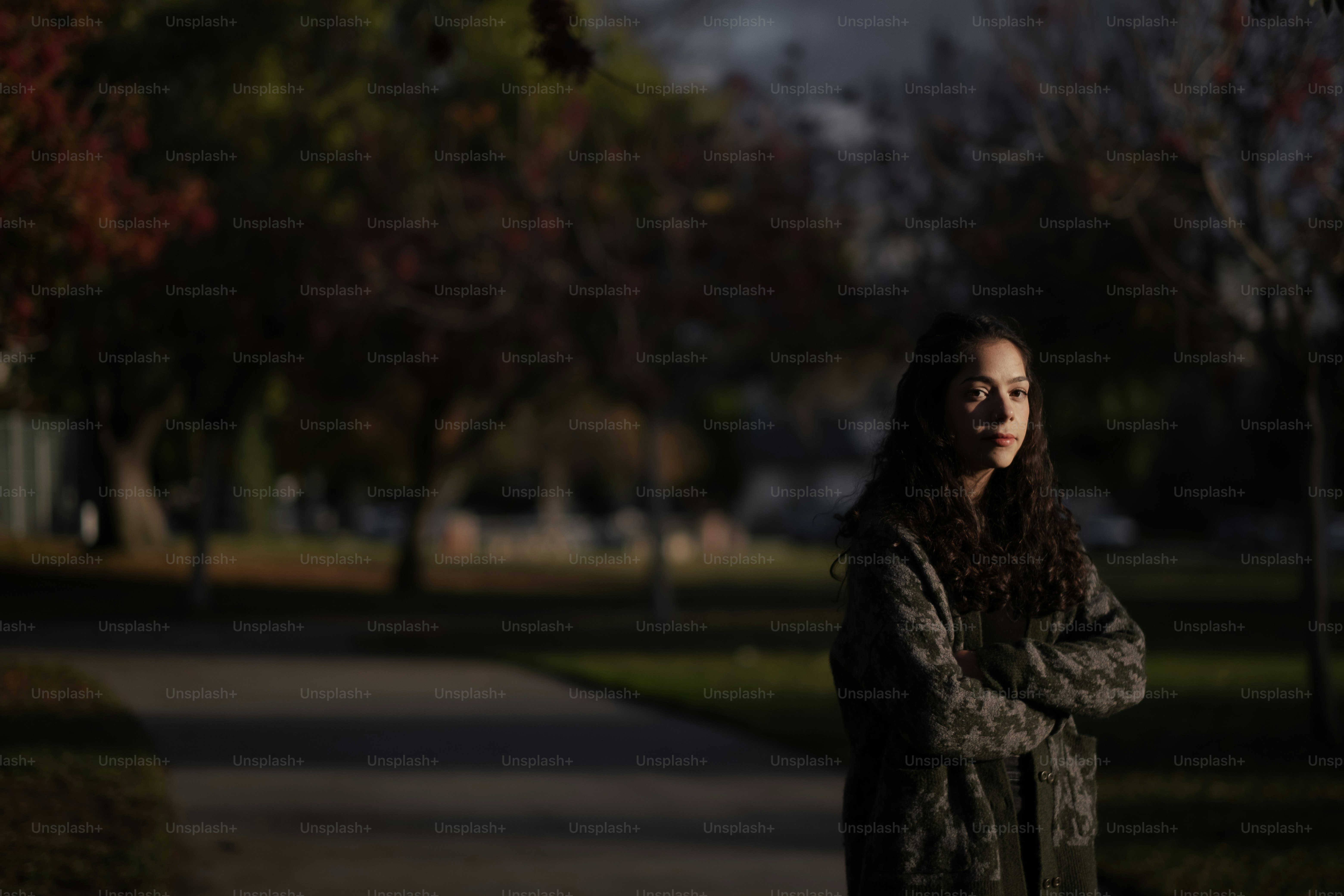 a woman standing on a sidewalk in a park